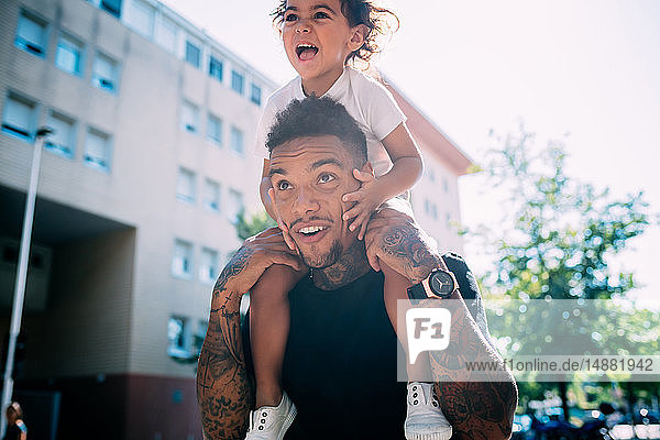 Father and son playing piggyback ride on sidewalk