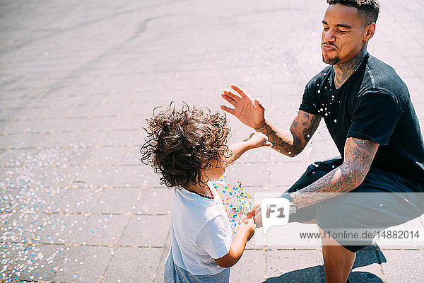 Father and son playing with confetti in park