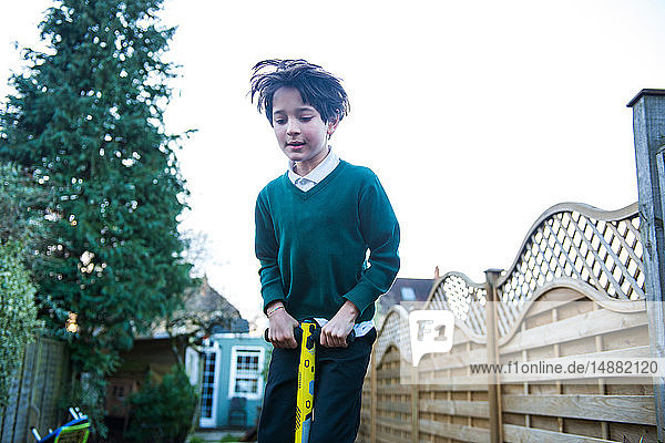 Junge springt auf Pogo-Stock im Garten