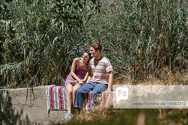 Junges Paar sitzt auf einer Mauer im Park  Los Angeles  Kalifornien  USA