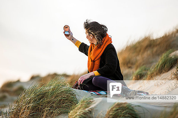 Woman looking at compact mirror on beach