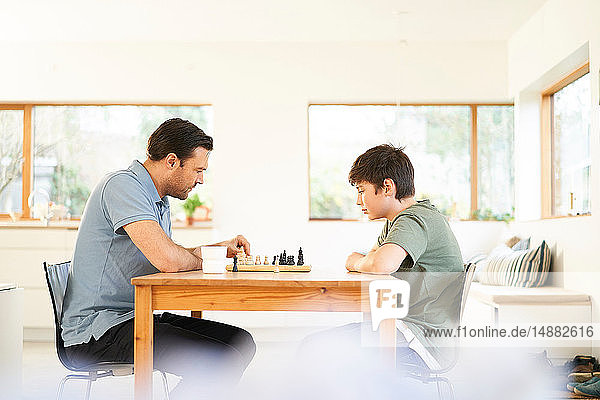 Junge und Vater spielen Schach am Wohnzimmertisch