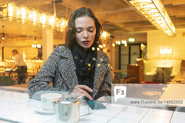 Young woman using smartphone in cafe  London  UK