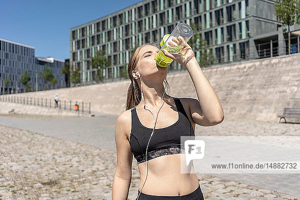 Junge Frau macht Pause von Sport und Trinkwasser in der Stadt  Berlin  Deutschland