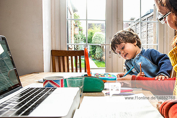 Toddler boy learning from mother working from home