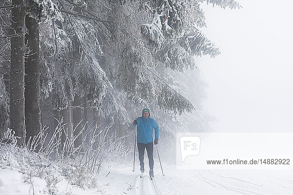 Skilanglauf eines erwachsenen Mannes durch Nebelwald  in voller Länge