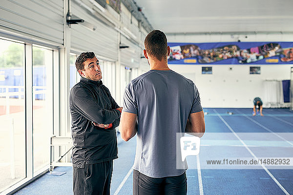 Trainer und Läufer sprechen in der Indoor-Laufbahn