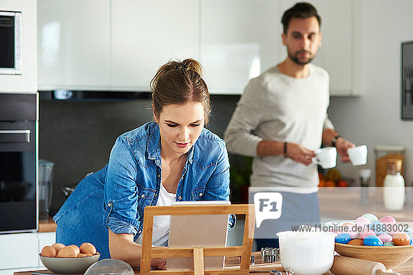 Ein Paar trinkt Kaffee und benutzt ein digitales Tablett in der Küche