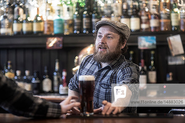 Barman serving beer to customer at bar in traditional Irish public house