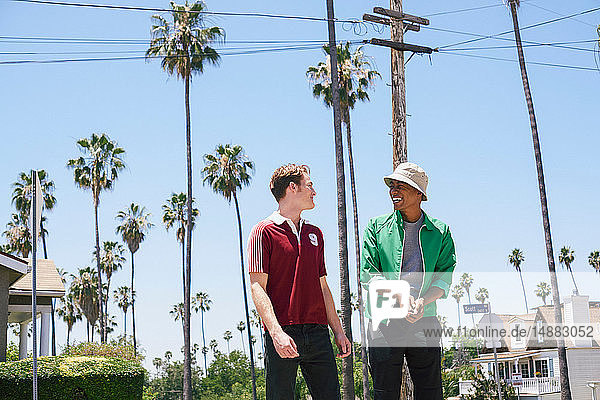 Zwei junge Männer gehen und sprechen in Vorstädten  Los Angeles  Kalifornien  USA