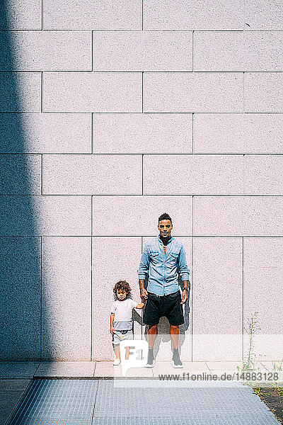 Father and son standing against concrete wall