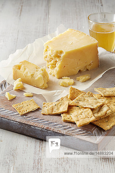 Still life with cheddar cheese and crackers on cutting board