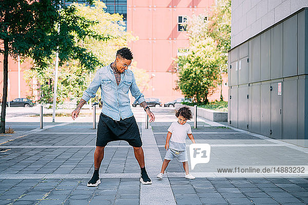 Father and son playing on sidewalk