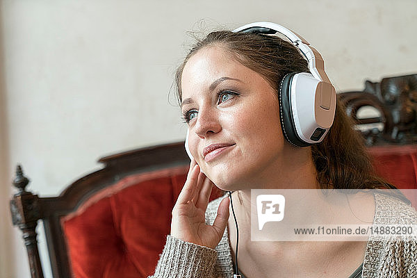 Junge Frau  die zu Hause mit Kopfhörern Musik hört