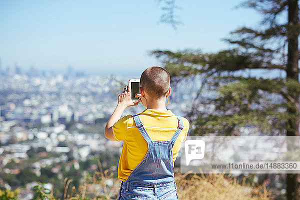 Teenage girl photographing view from cityscape hilltop  Los Angeles  California  USA