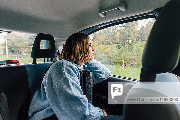 Frau  die auf dem Rücksitz eines Autos aus dem Fenster schaut