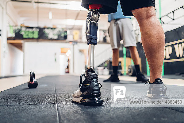 Mann mit Beinprothese und Freund im Fitnessstudio