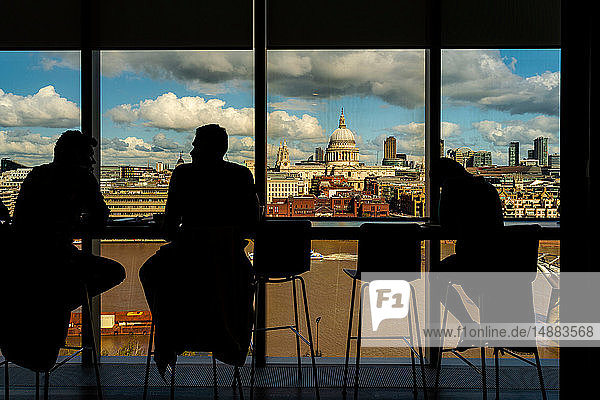 Silhouette of people having conversation by glass window  St Paul's Cathedral in background  City of London  UK