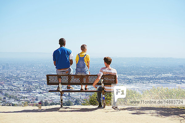 Drei junge erwachsene Freunde auf einer Hügelbank im Stadtbild  Rückansicht  Los Angeles  Kalifornien  USA
