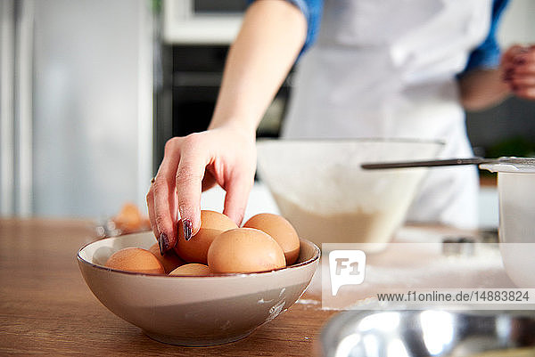Frau nimmt Ei aus Schüssel in Küche