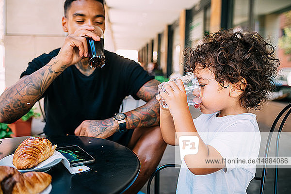 Father and son drinking in cafe