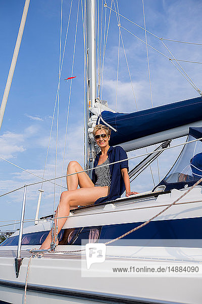 Mature woman sitting on sailboat on Chiemsee lake  portrait  Bavaria  Germany