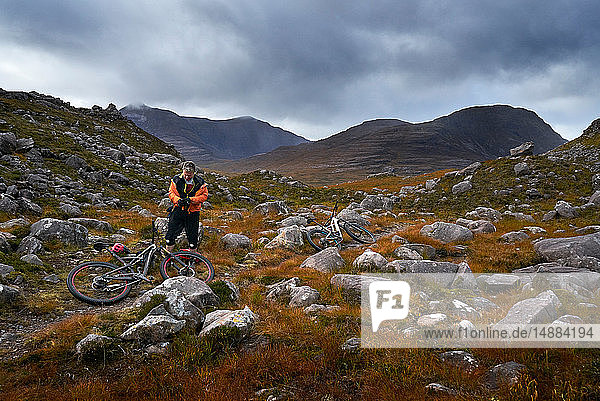 Männlicher Mountainbiker bei einer Pause in einer Bergtal-Landschaft  Achnasheen  Schottische Highlands  Schottland