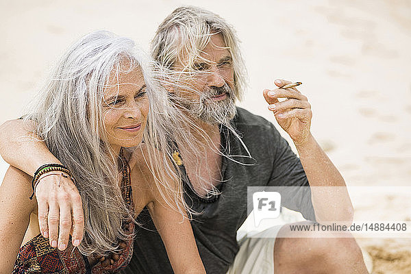 Porträt eines älteren Hippie-Paares beim Rauchen am Strand