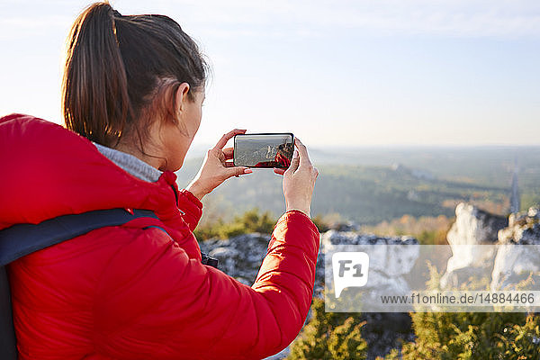 Frau auf einer Wanderung in den Bergen beim Fotografieren mit dem Smartphone