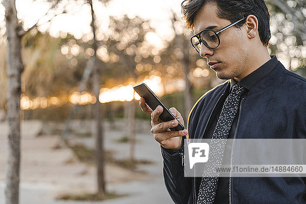 Modischer junger Geschäftsmann schaut auf Handy