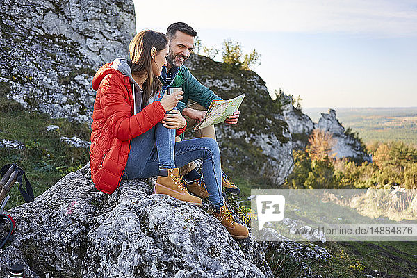 Glückliches Paar auf einer Wanderung in den Bergen macht eine Pause und schaut auf die Karte