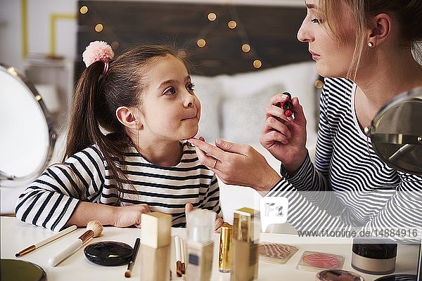 Mother and daughter applying make up together  using lipstick