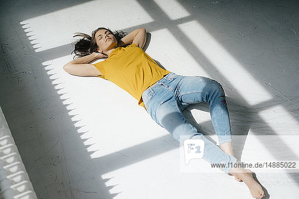 Frau liegt auf dem Boden und entspannt sich im Sonnenlicht