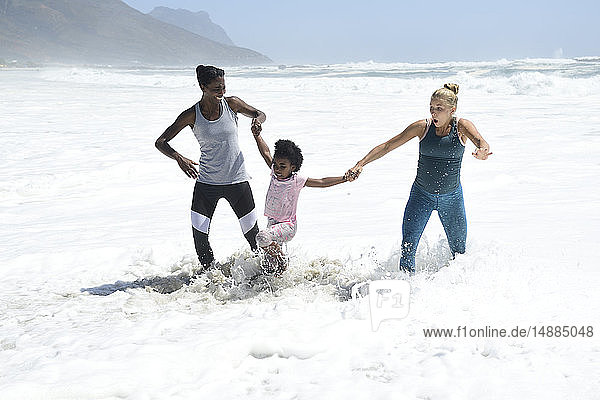 Mutter mit Tochter und Freundin haben Spaß beim Surfen am Strand