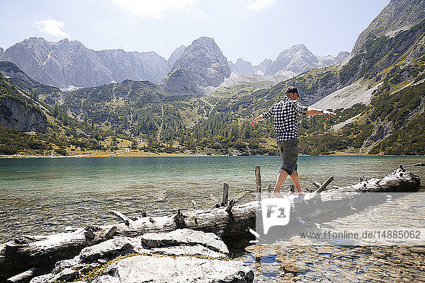 Austria  Tyrol  man balancing on tree trunk at lake Seebensee