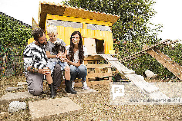 Portrait of happy family with Polish chicken at chickenhouse in garden