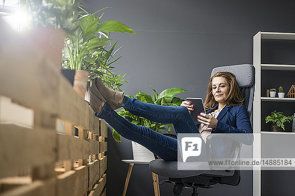 Reife Geschäftsfrau  die in einem nachhaltigen Büro arbeitet und ein digitales Tablet verwendet