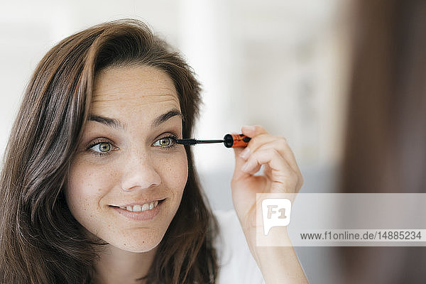 Pretty woman applying make up  using mascara
