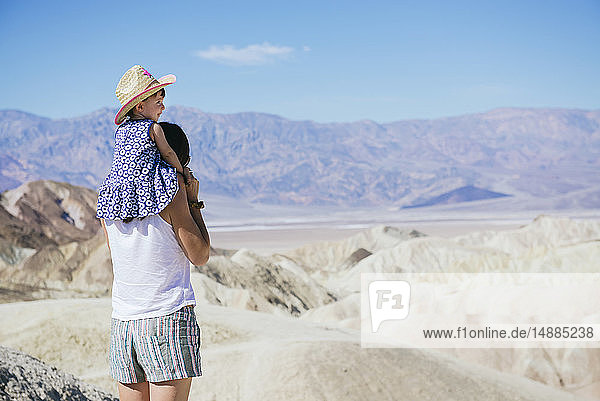 USA  Kalifornien  Death Valley National Park  Twenty Mule Team Canyon  Rückenansicht einer Mutter  die ein Mädchen trägt