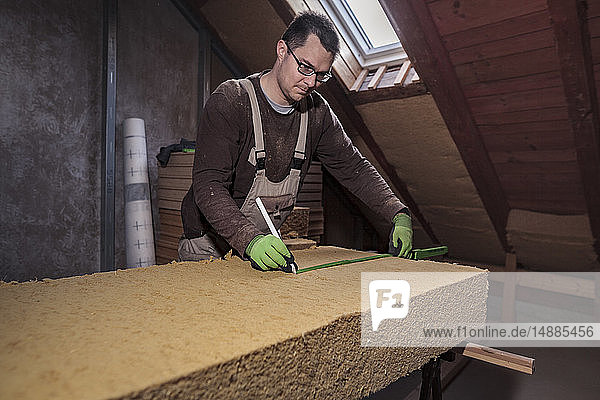 Dachisolierung  Arbeiter messen Holzfaserdämmung