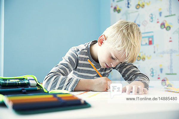 Focused boy doing homework at desk in children's room