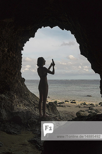 Young woman in cave  taking a photo