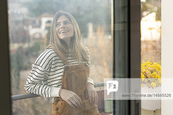 Porträt einer lächelnden jungen Frau  die sich auf dem Balkon entspannt