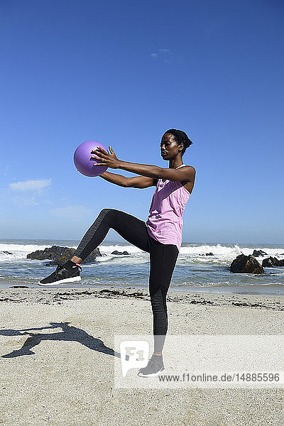 Frau beim Fitnesstraining mit Ball am Strand