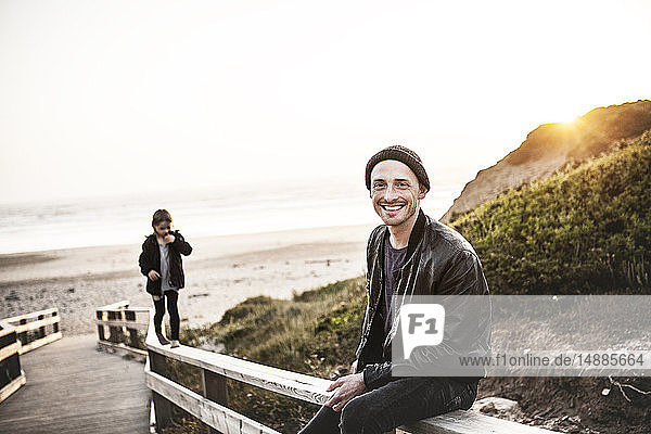 Portrait of smiling man with daughter on boardwalk near the beach