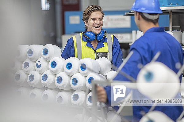 Arbeiter in reflektierender Weste lächelt Kollege in der Fabrik an