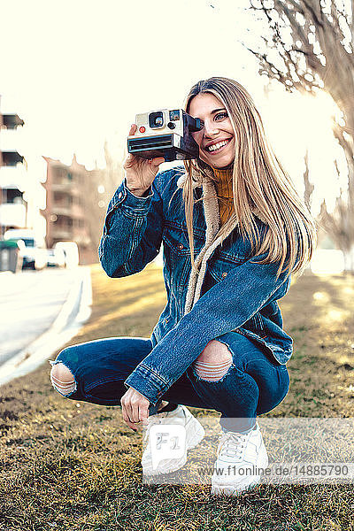 Porträt einer lächelnden jungen Frau mit Sofortbildkamera