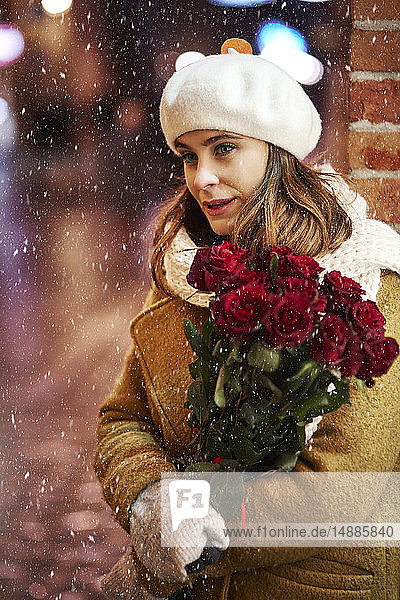 Porträt einer jungen Frau mit einem Strauss roter Rosen im Winter