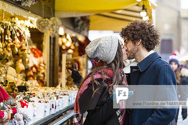 Glückliches  liebevolles  junges Paar küsst sich auf dem Weihnachtsmarkt