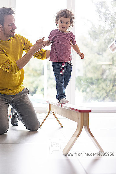 Vater hilft seiner Tochter  auf einem Balken zu balancieren